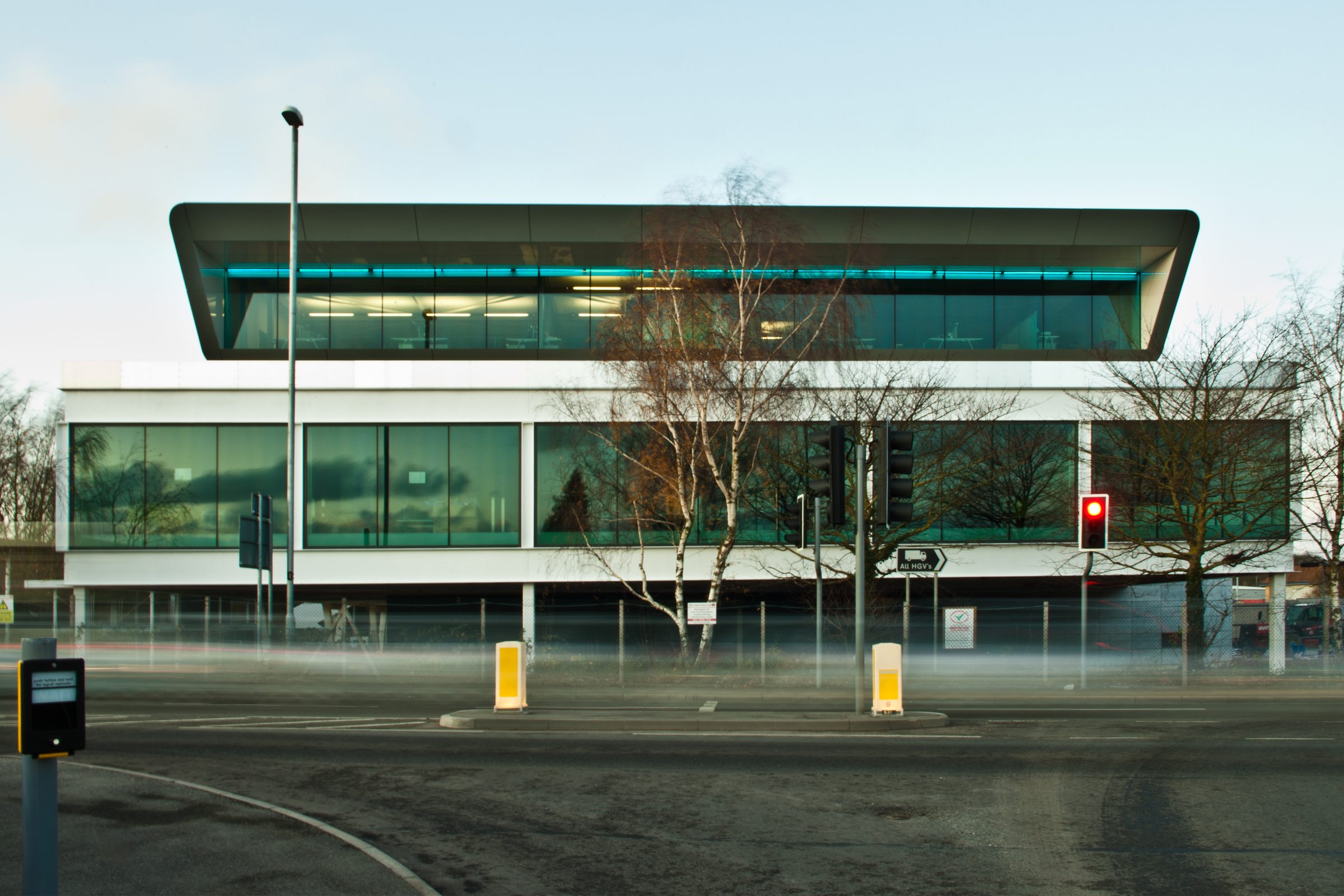 Ashfield House's cantilevered upper floor and angled roof edge photographed at dusk from street level, with light trails from passing traffic