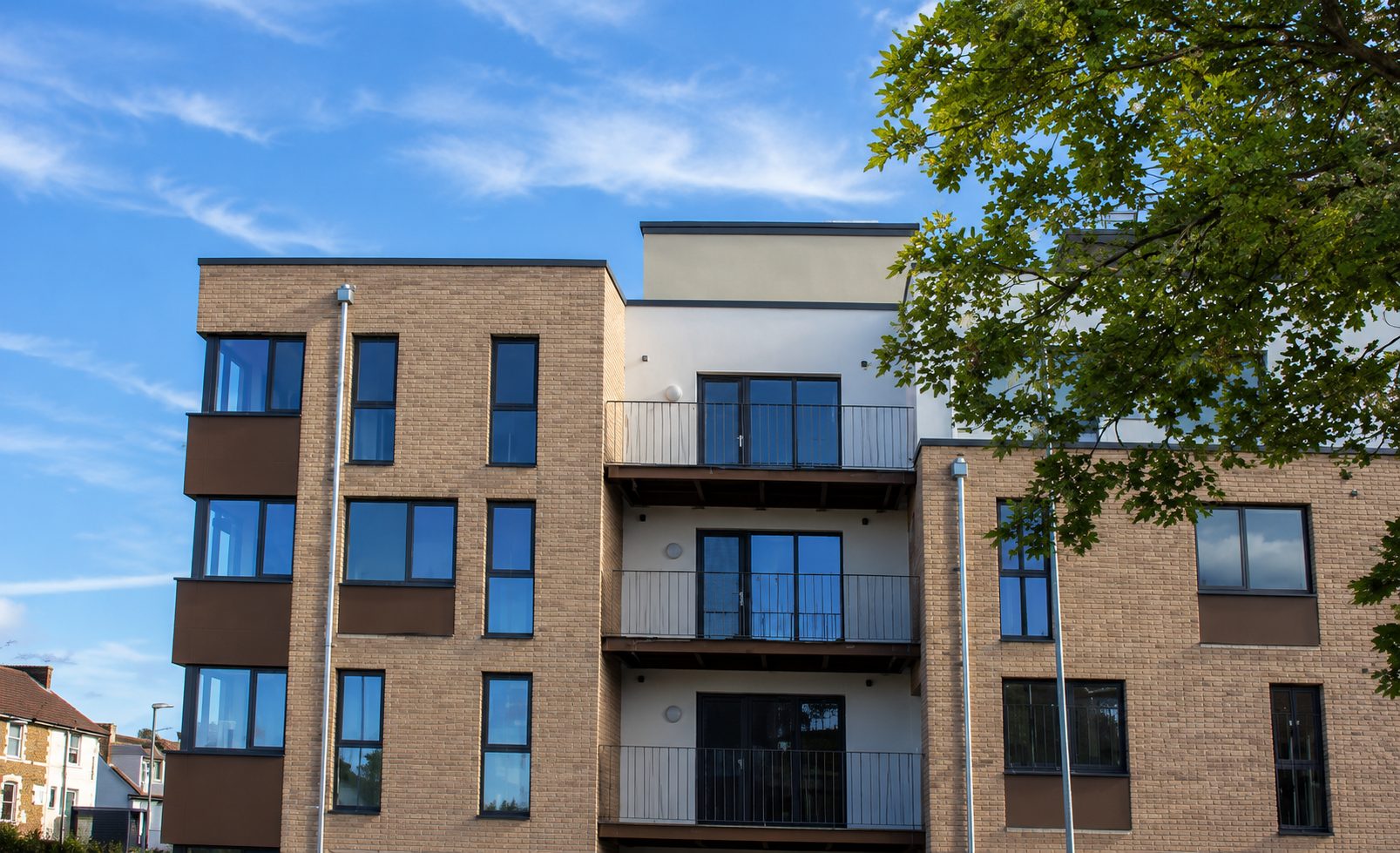 Buff brick-slip elevations with dark window bands and a rendered balcony recess on a new apartment wing of The Panorama, Ashford