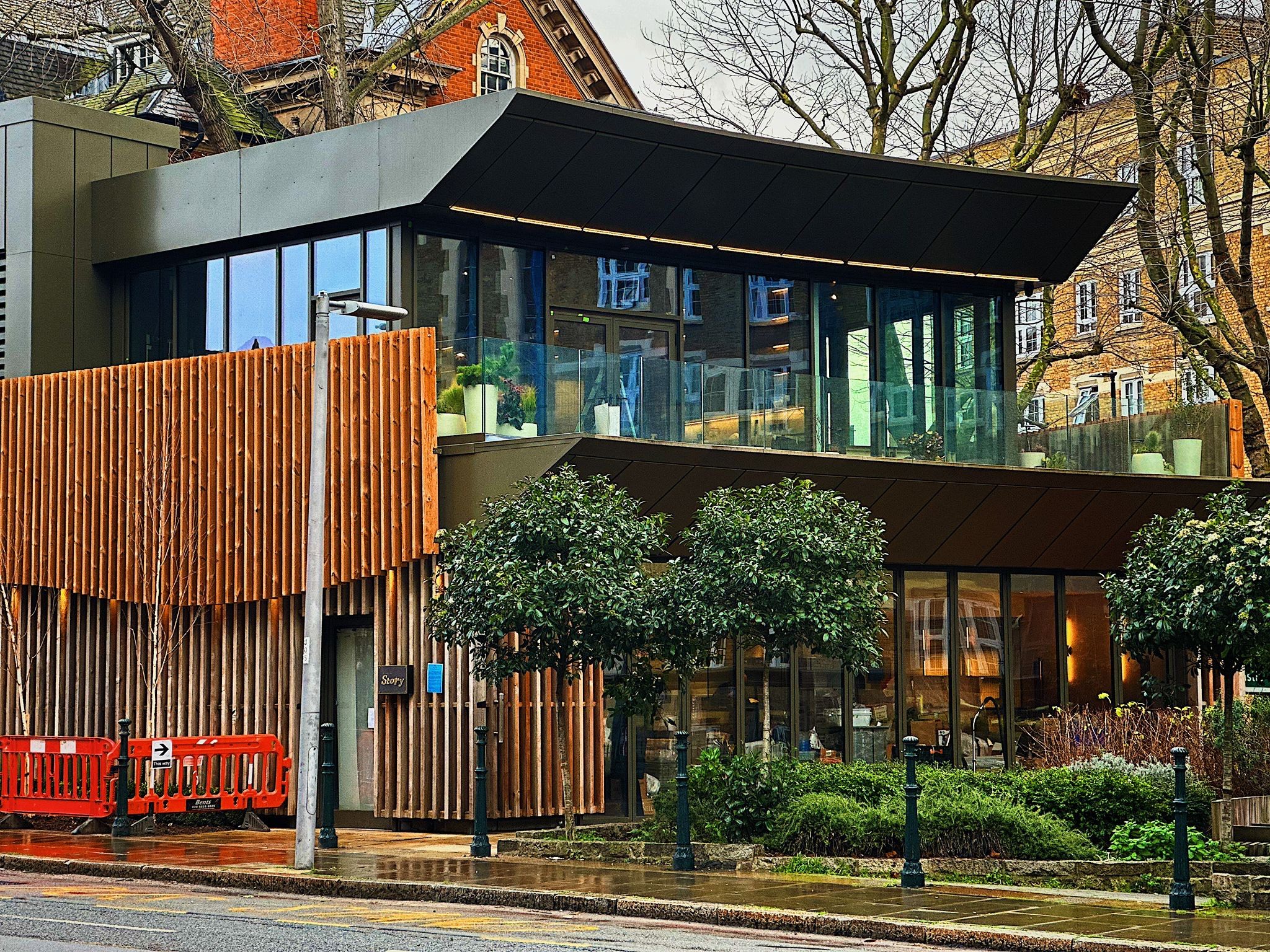 Dark metal fascia and deep soffit over the glazed upper storey of Restaurant Story, above timber screening on Tooley Street