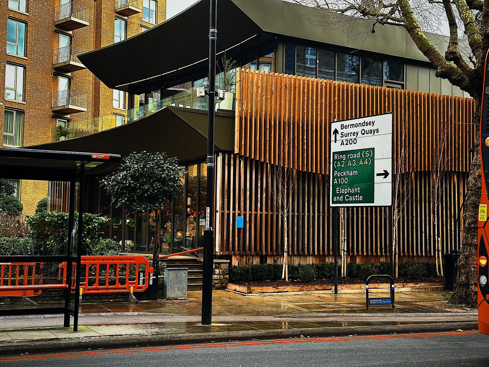 Restaurant Story from Tooley Street: a glazed upper storey and dark metal roof behind a curved slatted timber screen, a road sign in front